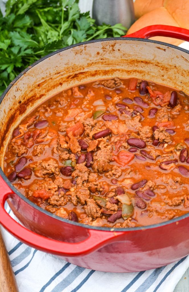 cheeseburger chili shown in a red dutch oven with a wooden spoon for serving