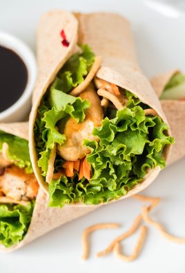 Asian chicken wraps served on a white plate with a dark sauce for dipping