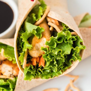 Asian chicken wraps served on a white plate with a dark sauce for dipping