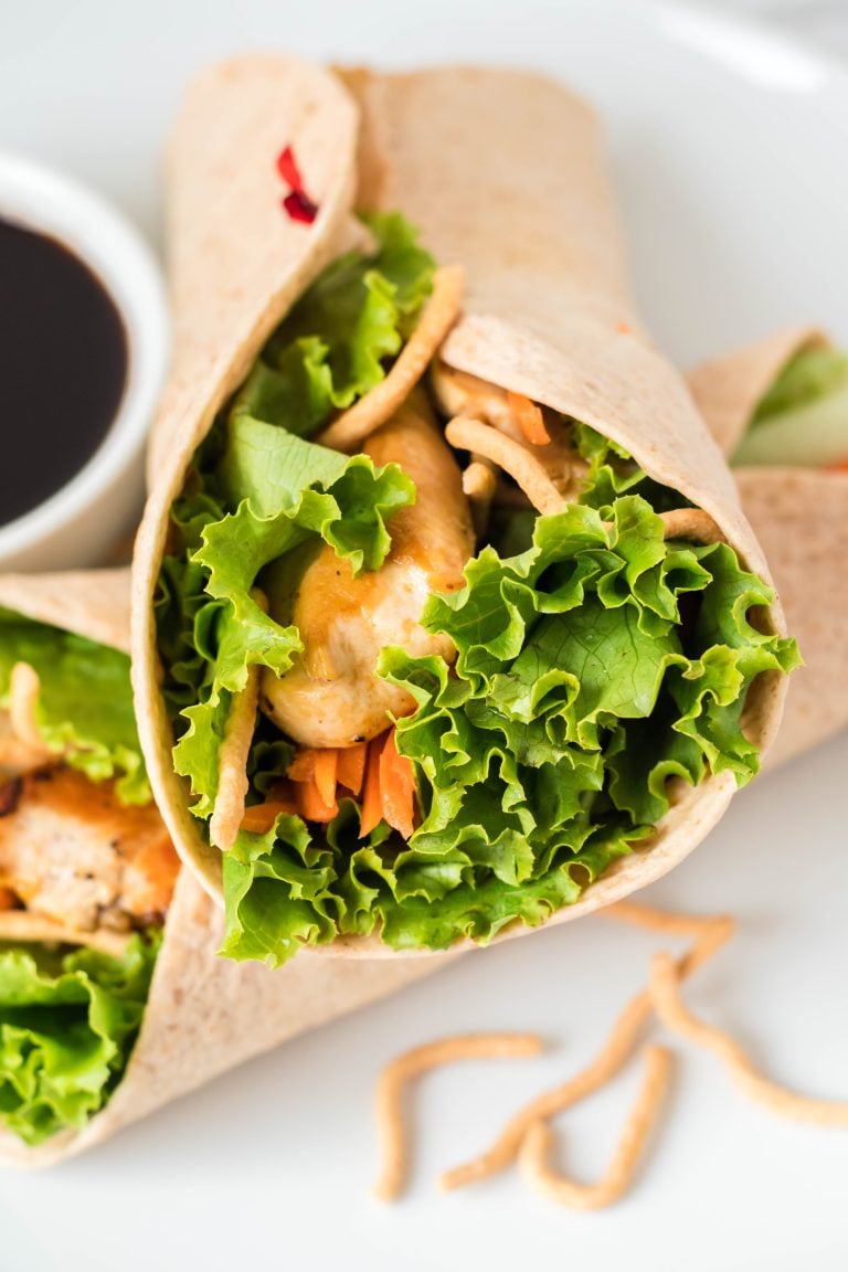 Asian chicken wraps served on a white plate with a dark sauce for dipping