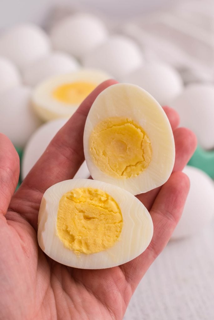 a hand holding up a halved hard boiled egg made in the air fryer