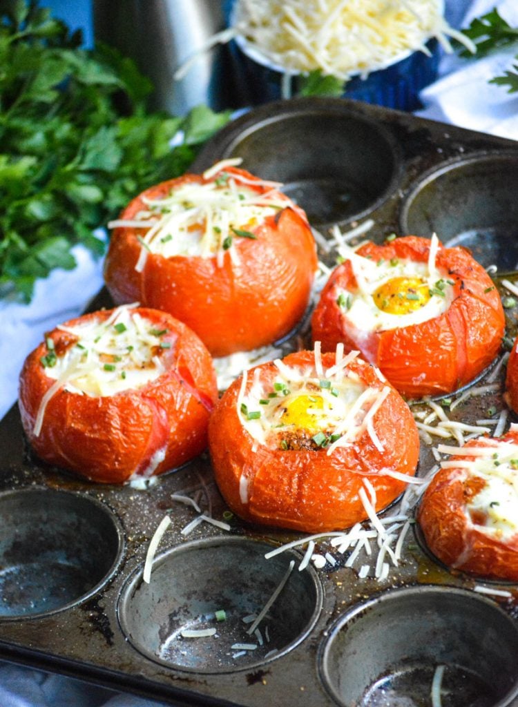 egg stuffed baked tomatoes shown in a muffin tin pan