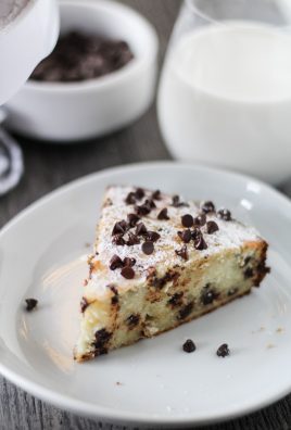 a slice of Italian ricotta cake shown on a white plate and sprinkled with miniature chocolate chips