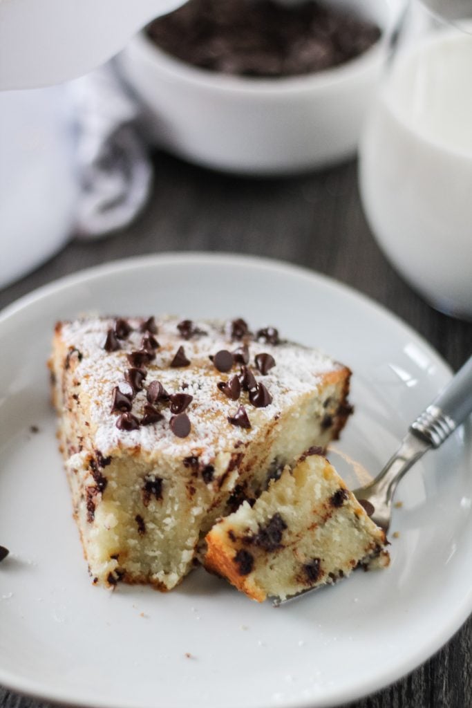 a slice of chocolate chip Italian ricotta cake shown on a white plate with a forkful removed
