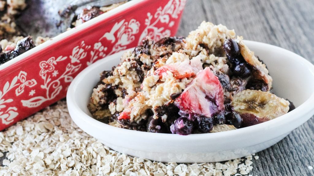 a serving of banana berry breakfast bake shown in a white oval bowl