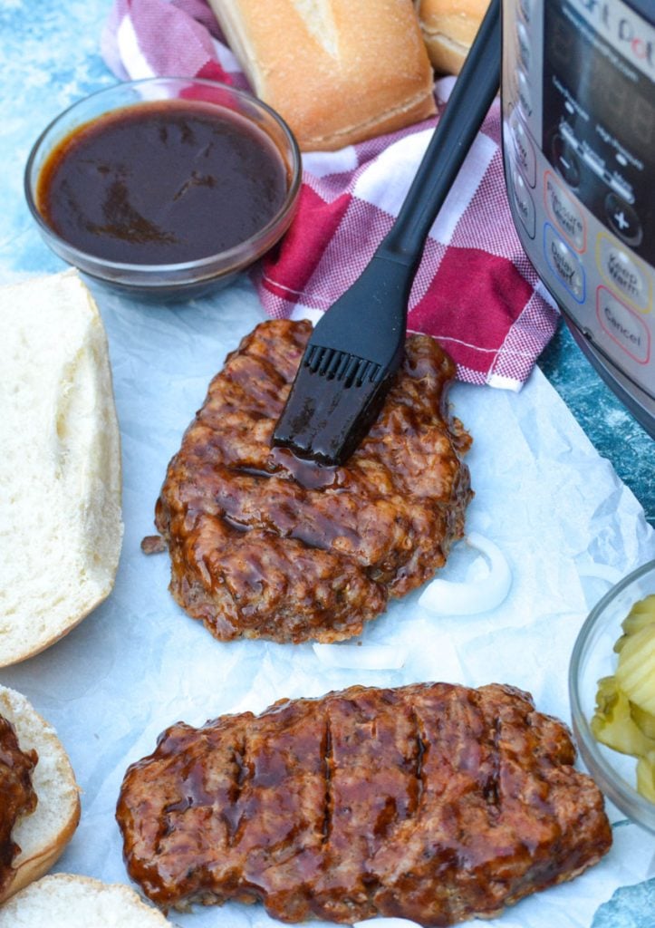 a silicone brush shown spreading barbecue sauce onto a pressure cooked pork patty