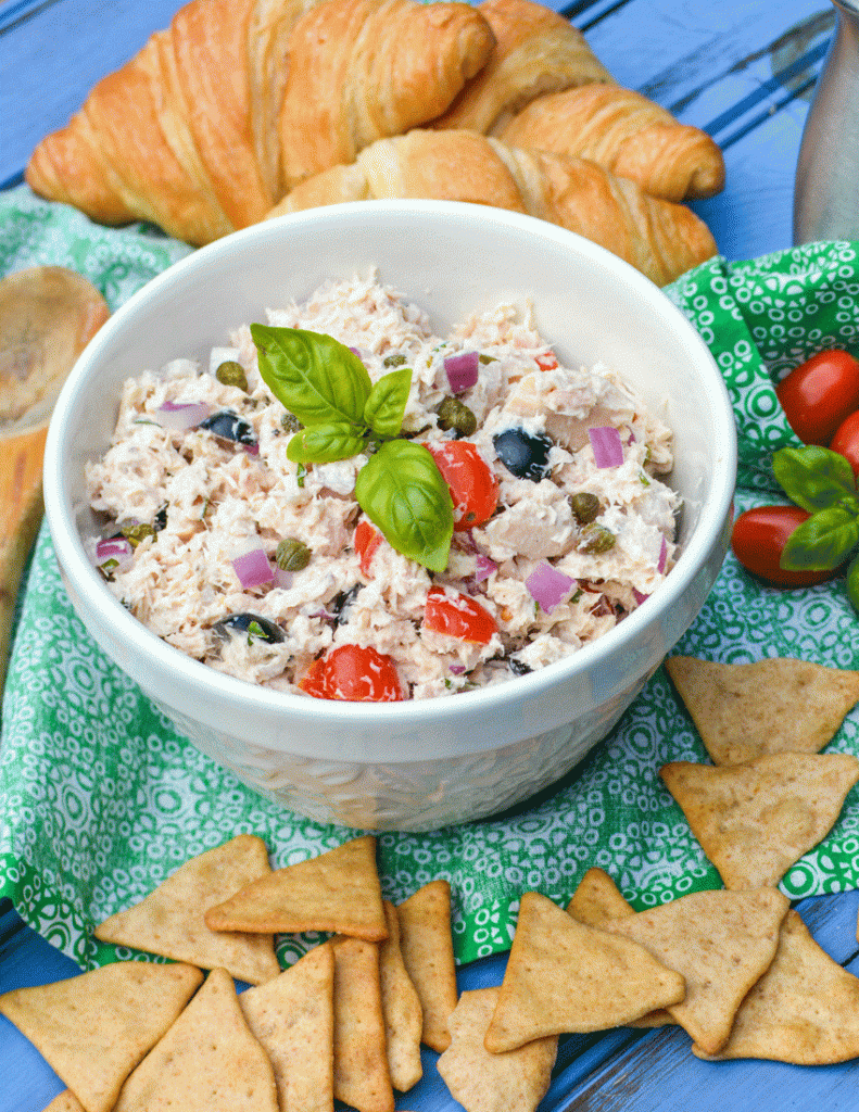 Italian tuna salad in a white ceramic bowl topped with fresh basil leaves