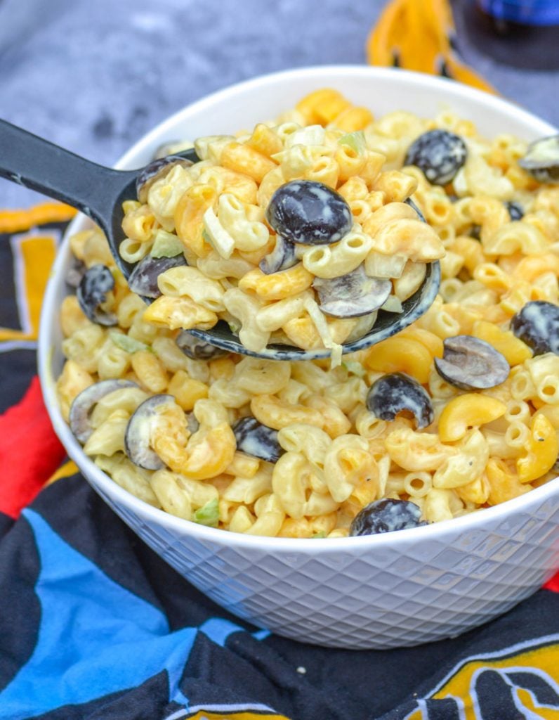 a black serving spoon holding aloft a scoop of pittsburgh steelers pasta salad