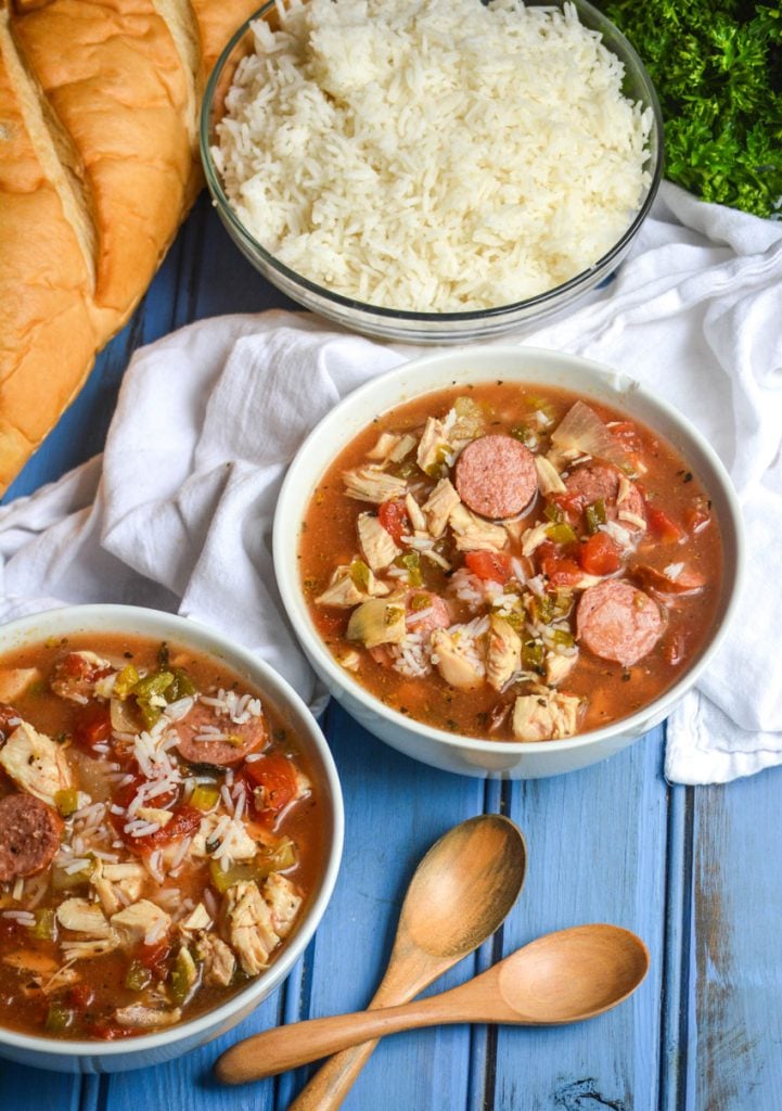 slow cooker jambalaya soup served in white bowls with wooden spoons on the side