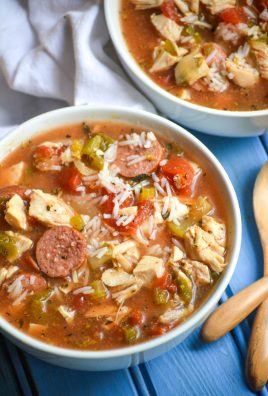 slow cooker jambalaya soup served in white bowls with wooden spoons on the side