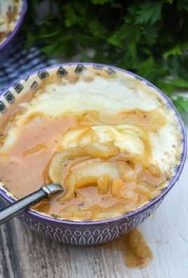a classic bistro style french onion soup served in a bowl with a spoon and topped with a layer of melted cheese