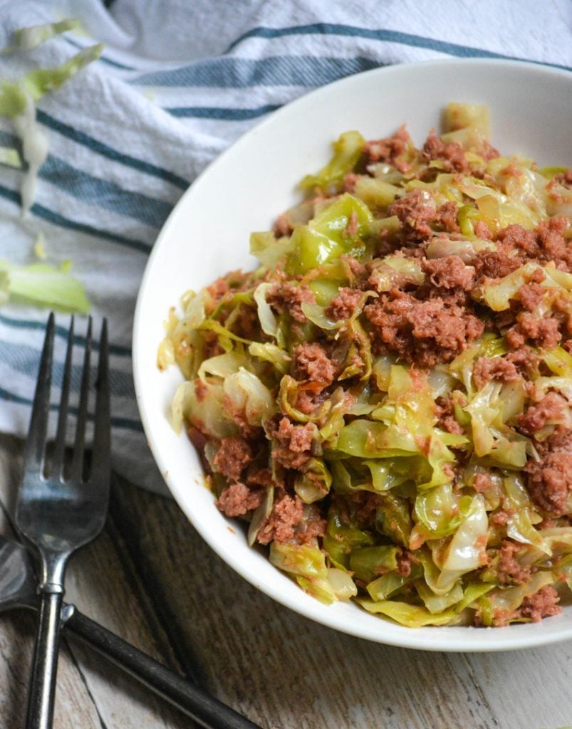 corned beef & cabbage served in a white bowl with a silver fork on the side