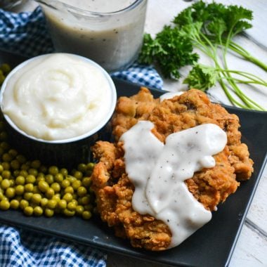 country fried steak with pepper gravy served on a black plate