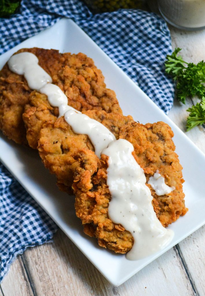 country fried steak with gravy shown on a white serving platter