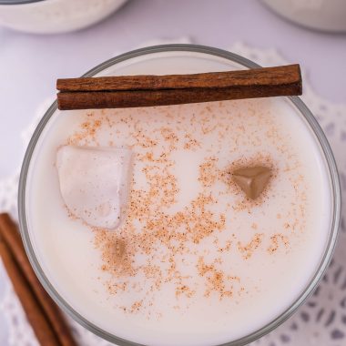 traditional horchata served in a clear glass with ice and topped with a pinch of ground cinnamon for garnish