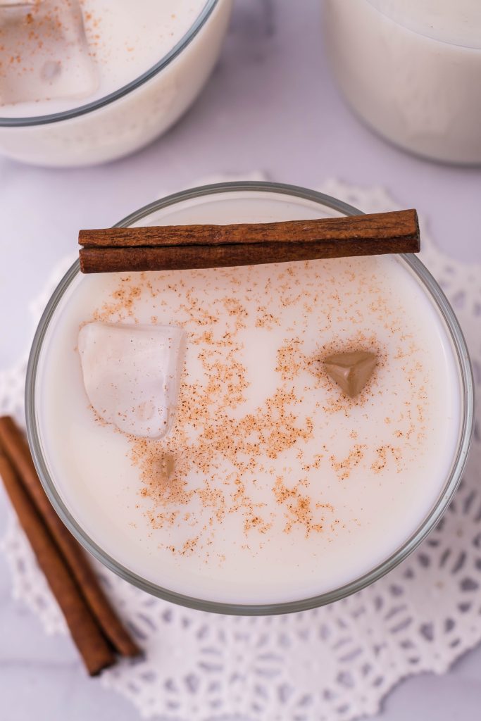 traditional horchata served in a clear glass with ice and topped with a pinch of ground cinnamon for garnish