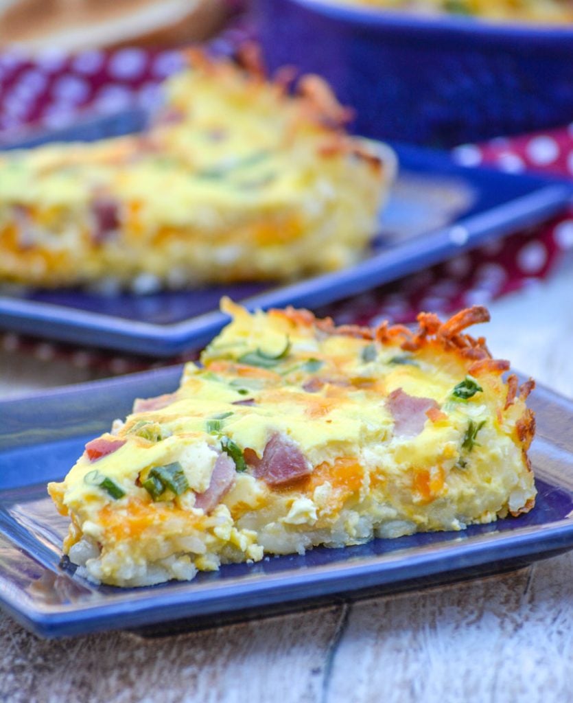 slices of ham and cheese hash brown crusted quiche on blue square plates