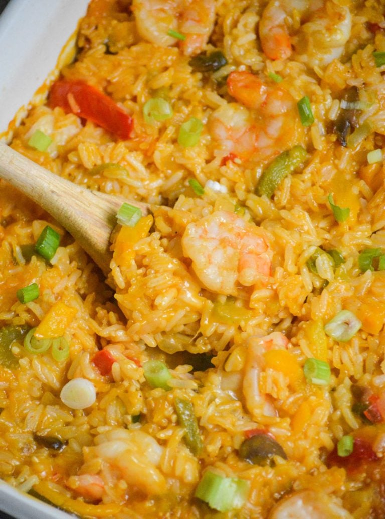 shrimp & rice casserole with a wooden spoon shown serving