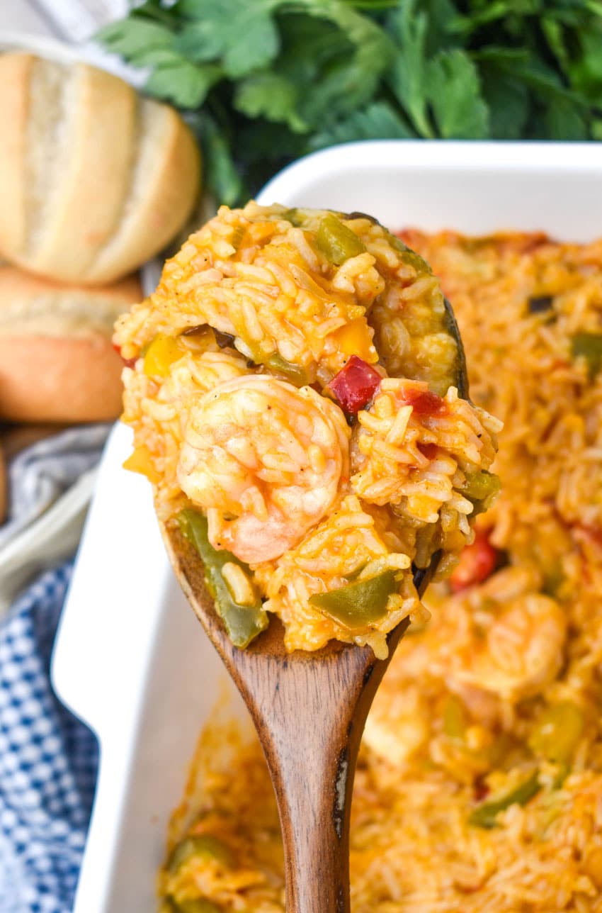 a wooden spoon holding up a scoop of shrimp and rice casserole