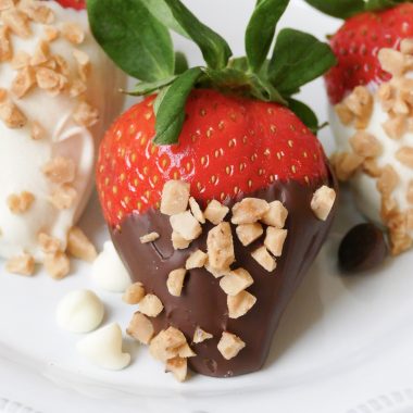 hand dipped chocolate covered strawberries sprinkled with toffee chips and served on a white plate