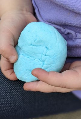a sky blue colored ball of peeps playdough shown in held in two little toddler hands