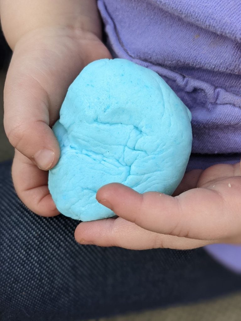 a sky blue colored ball of three ingredient edible peeps playdough shown in held in two little toddler hands