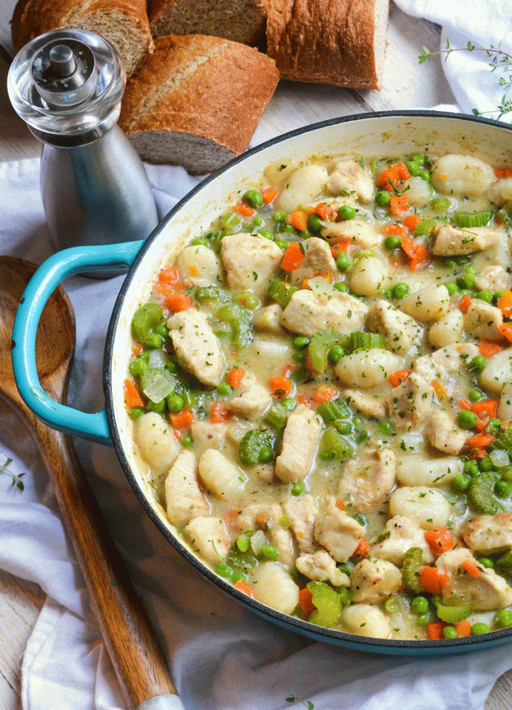 chicken & gnocchi dumplings shown in a blue enameled skillet surrounded by crusty slices of bread