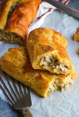 a classic sausage roll shown on a piece of parchment paper and broken open to reveal the creamy sausage filling inside