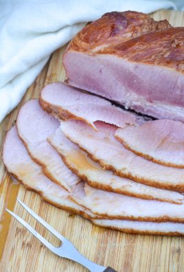 crockpot glazed ham shown sliced on a wooden cutting board and drizzled with juices