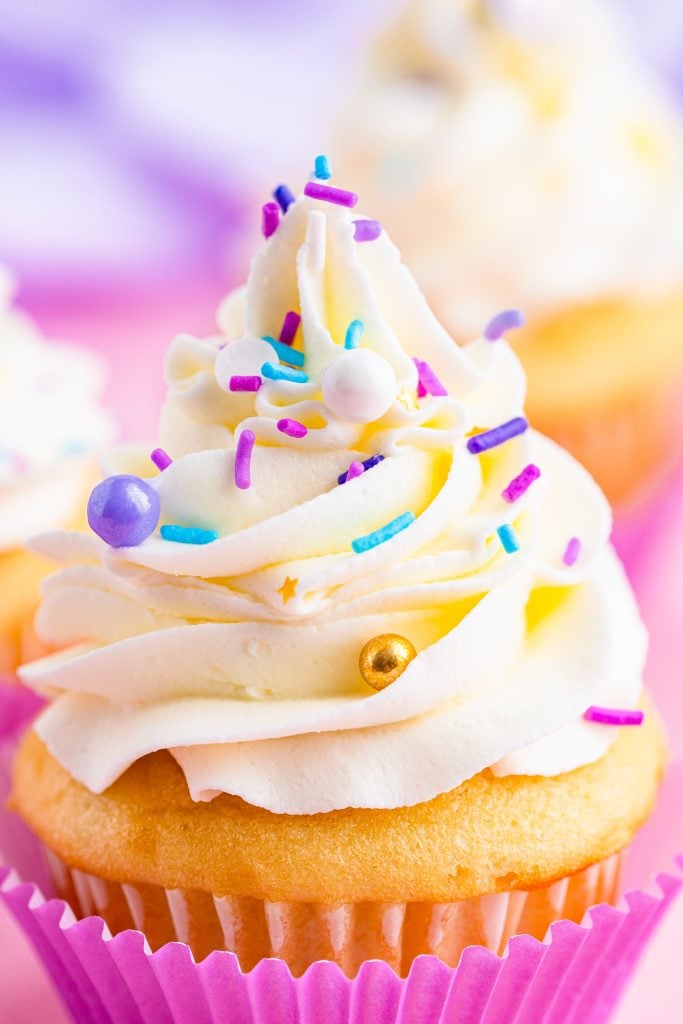 close up of a cupcake piled high with swirls of fluffy cake decorating frosting