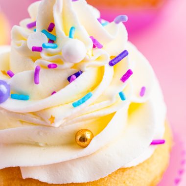 close up of a cupcake piled high with swirls of fluffy cake decorating frosting