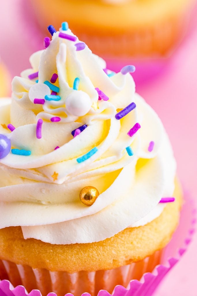 close up of a cupcake piled high with swirls of fluffy cake decorating frosting