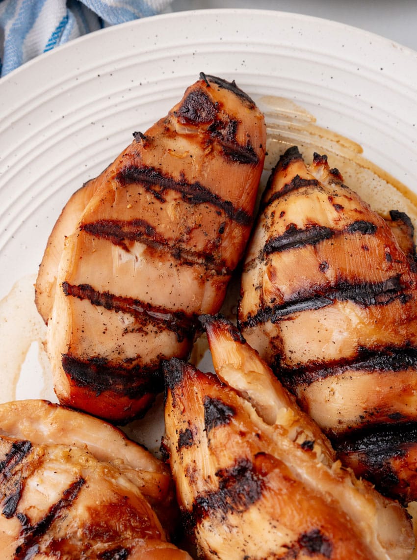 a close up of grilled teriyaki chicken breasts on a white serving plate