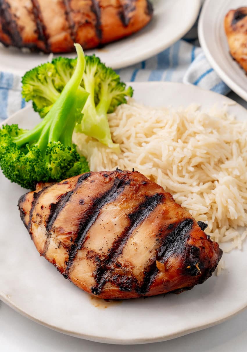 a grilled teriyaki chicken breast with white rice and steamed broccoli on a white plate