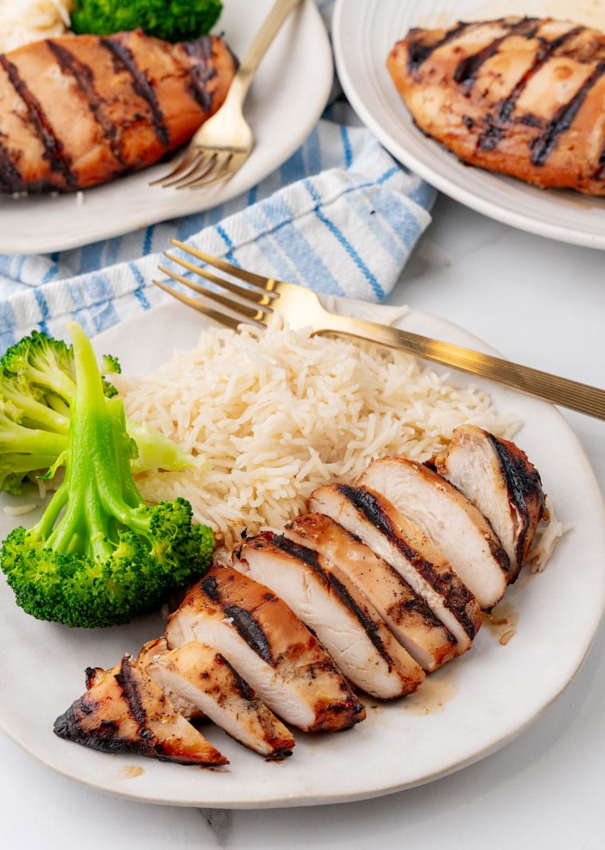 a grilled teriyaki chicken breast with white rice and steamed broccoli on a white plate