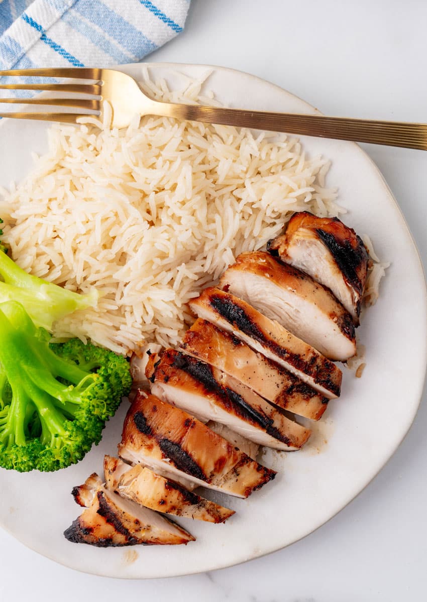 a grilled teriyaki chicken breast with white rice and steamed broccoli on a white plate