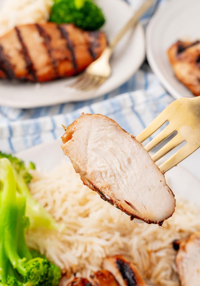 a gold fork holding up a slice of grilled teriyaki chicken