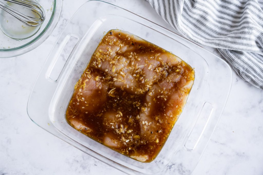 grilled chicken teriyaki shown in a glass pyrex bowl marinating in sauce before being grilled