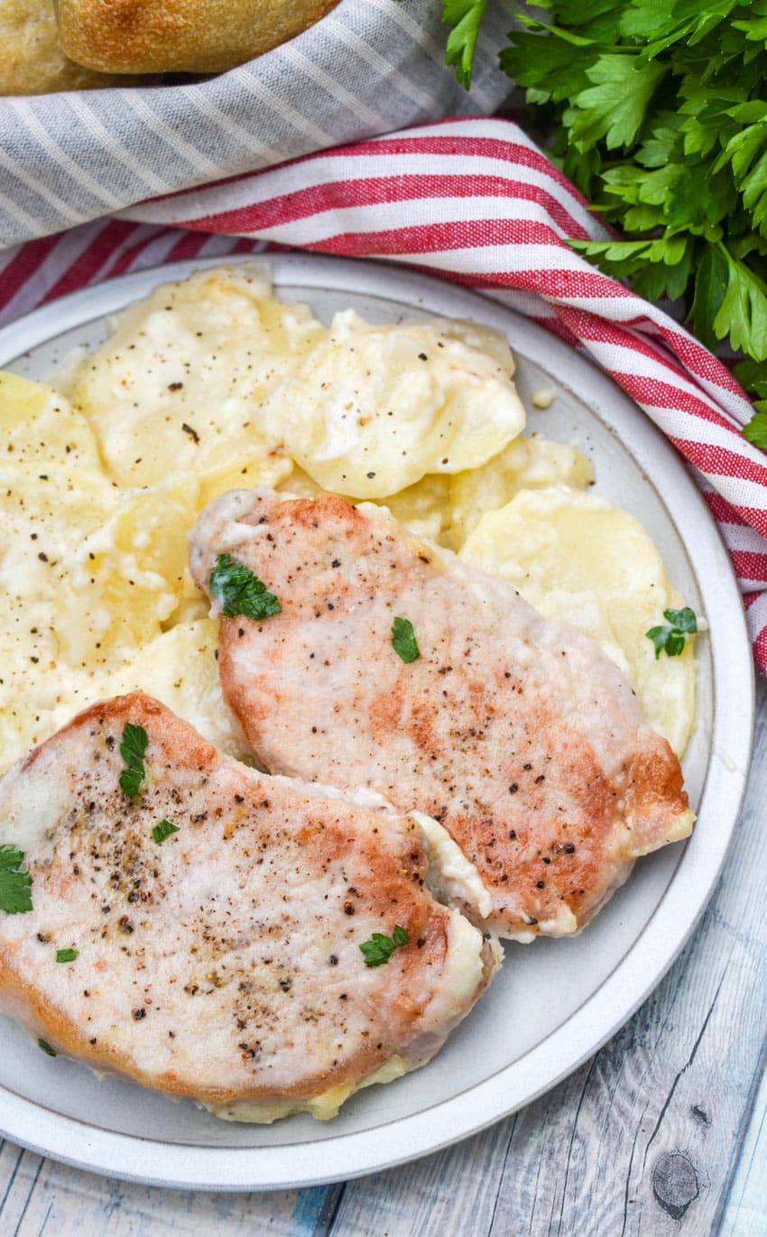 baked pork chops and potatoes on a white dinner plate with a silver fork resting on the side