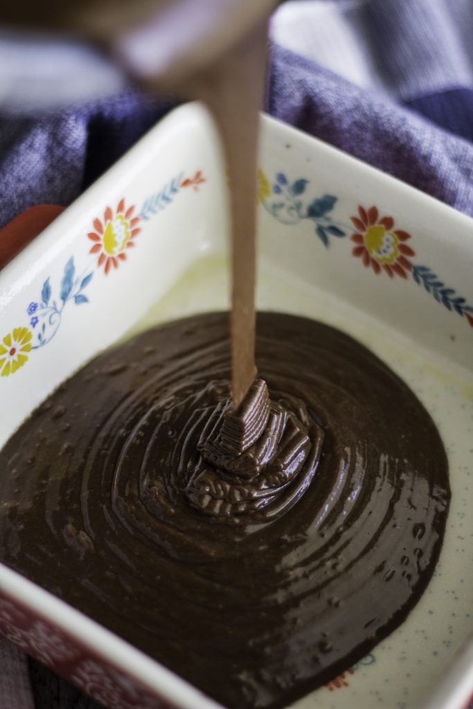 chocolate depression cake batter being poured into a prepared baking dish