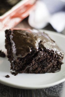 a slice of rich chocolate depression cake topped with fudgy ganache and served on a white plate
