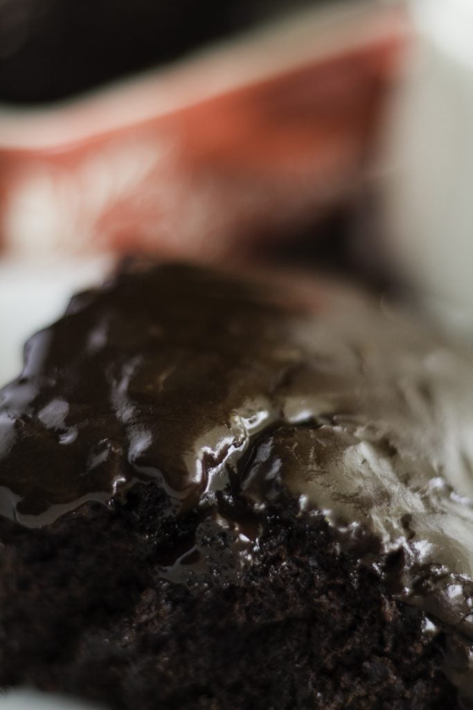 close up of a thick slice of chocolate depression cake topped with rich chocolate ganache