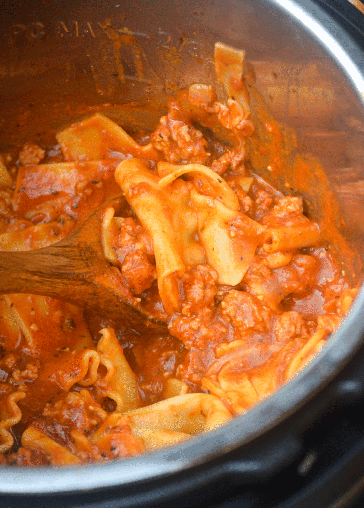 a wooden spoon shown scooping lazy lasagna out of the silver liner of an Instant Pot