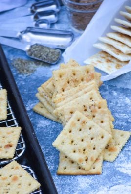 a loose pile of savory Italian seasoned saltine crackers shown in the center or a blue counter with all of the ingredients staged evenly around them