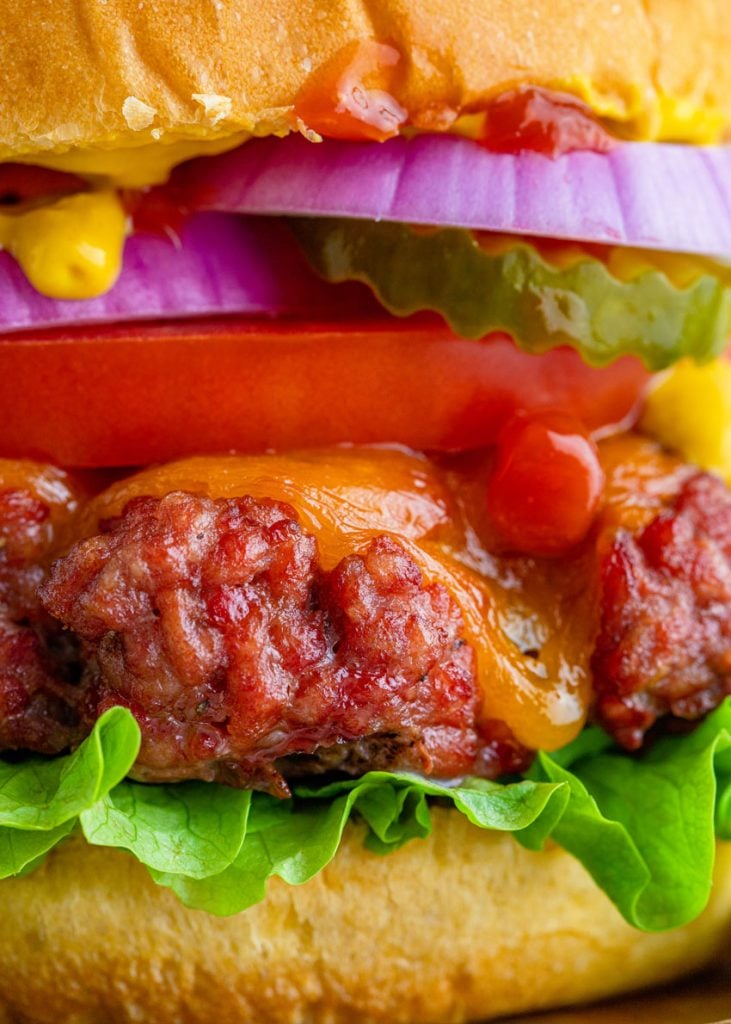 a close up shot of a fully loaded smoked cheeseburger