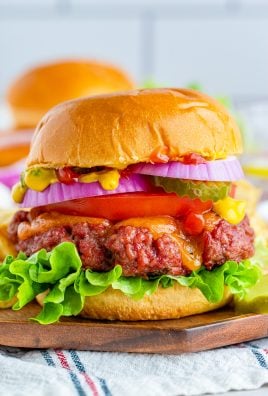 a smoked burger shown in a fluffy bun piled high with vibrant, fresh fixings and served on a wooden cutting board