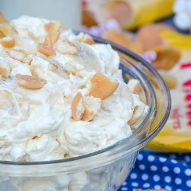 banana pudding fluff salad shown in a glass pyrex bowl topped with chopped vanilla wafers cookies