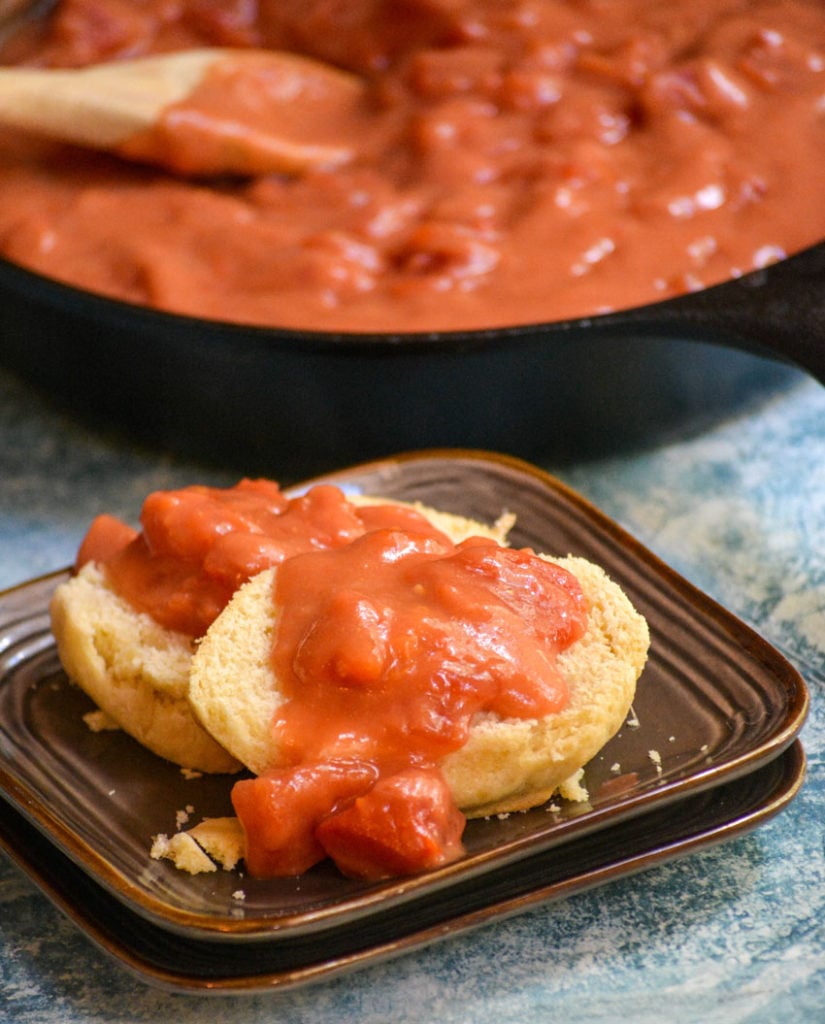 buttermilk biscuits cut in half and covered with Southern tomato gravy on a small brown plate