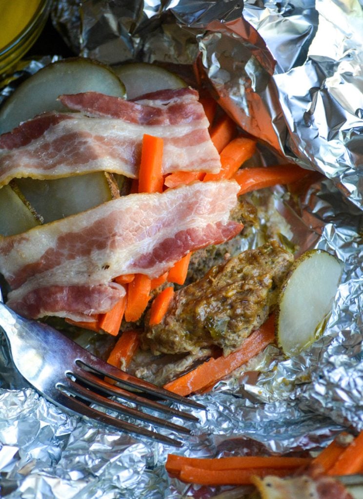 a close up of an unwrapped hobo hamburger foil packet with a silver fork