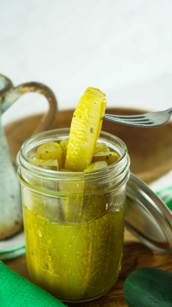 a fork lifting a seasoned ranch pickle out of a glass mason jar
